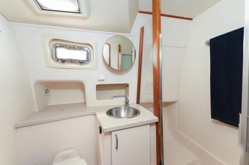  Yacht Photos Pics Bathroom interior of 2005 Mainship 400 Trawler with sink, mirror, and porthole window.