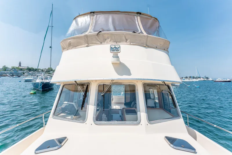  Yacht Photos Pics 2005 Mainship 400 Trawler on water, clear sky, marina in background.