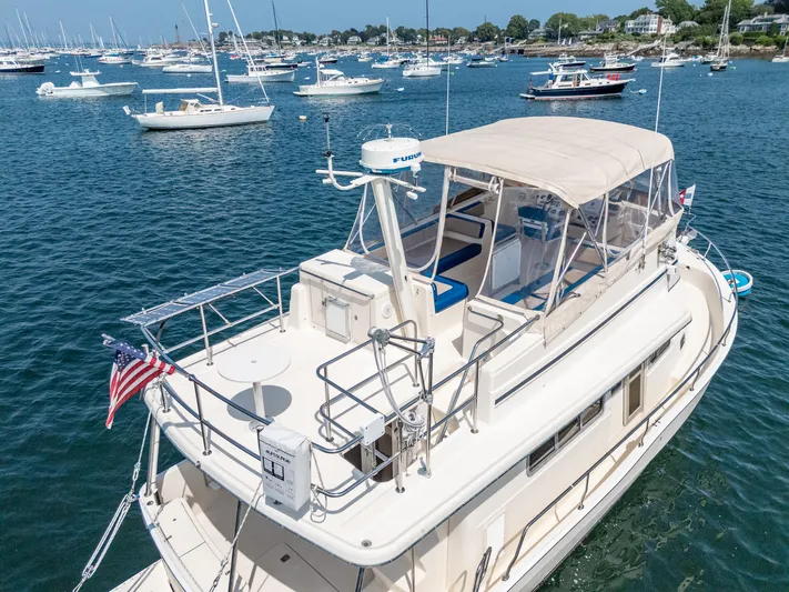  Yacht Photos Pics 2005 Mainship 400 Trawler on water, surrounded by boats, with American flag.