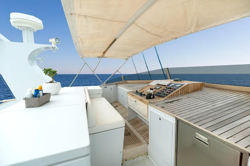 Anonymous Yacht Photos Pics Luxurious yacht deck with wooden controls, ocean view, and canopy, Hellenic Shipyards Custom 1981.