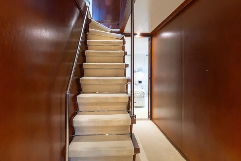 Anonymous Yacht Photos Pics Interior staircase on 1981 Hellenic Shipyards custom yacht, featuring wooden walls and carpeted steps.