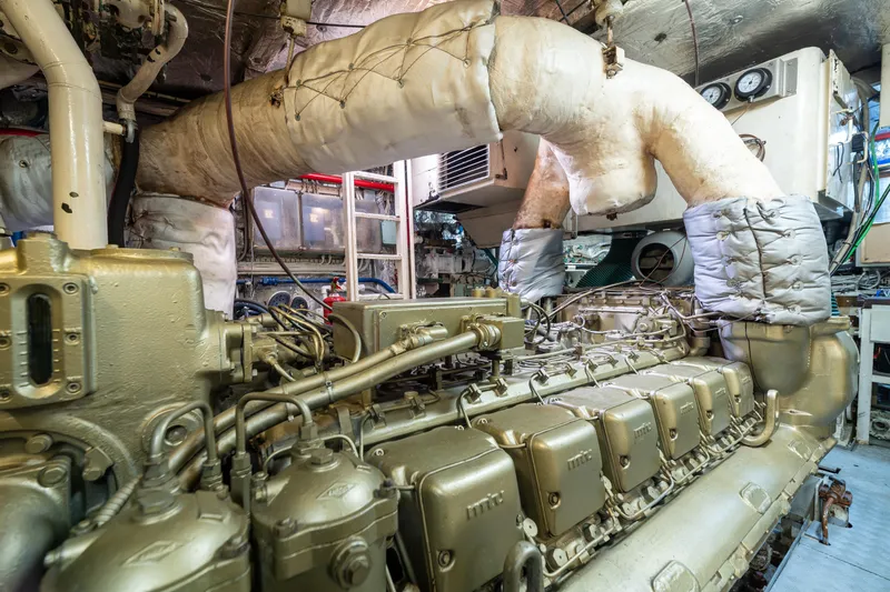 Anonymous Yacht Photos Pics Engine room of 1981 Hellenic Shipyards Custom vessel, showcasing complex machinery and insulated pipes.