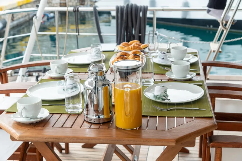 Anonymous Yacht Photos Pics Elegant breakfast setup on a yacht, featuring orange juice and pastries, Hellenic Shipyards Custom 1981.
