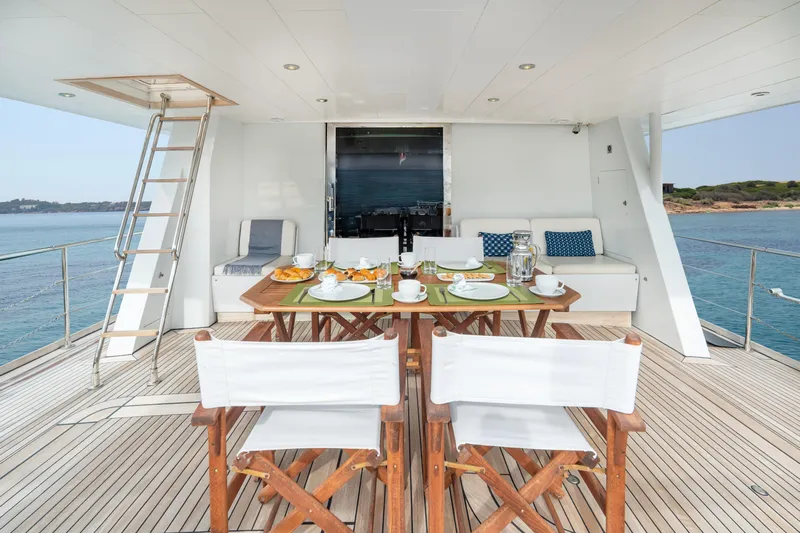 Anonymous Yacht Photos Pics Luxurious yacht deck with dining setup, featuring wooden chairs and ocean view, Hellenic Shipyards Custom 1981.