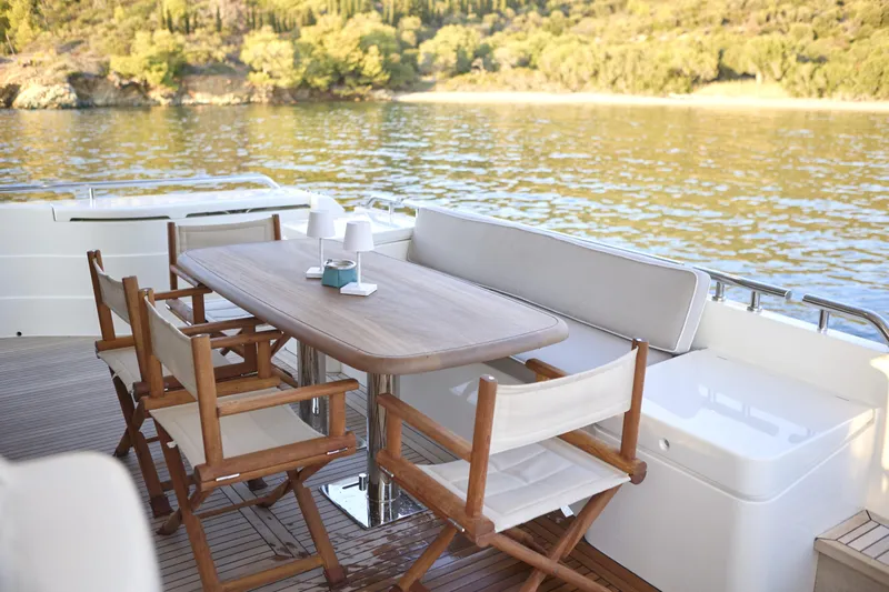  Yacht Photos Pics Outdoor dining area on 2004 Ferretti Yachts 680, overlooking serene water and lush greenery.