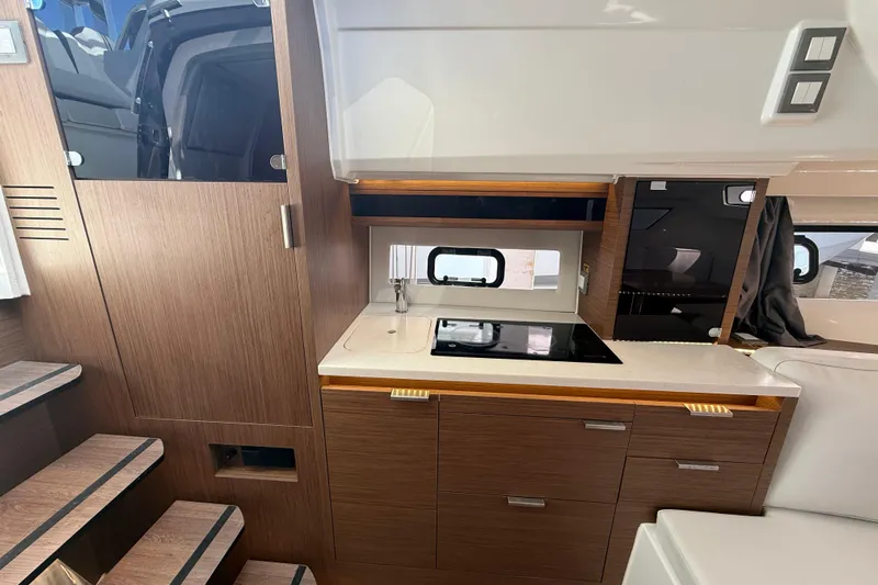  Yacht Photos Pics 2022 Jeanneau Leader 10.5 WA Series 2 interior kitchen with modern wood cabinetry and compact design.