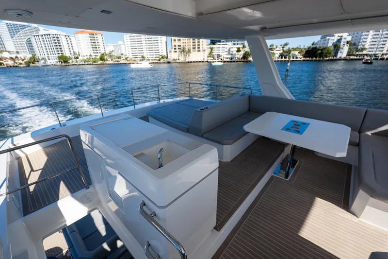 The Office Yacht Photos Pics Luxurious 2021 Leopard 53 Powercat yacht interior with seating and table, cruising near cityscape.
