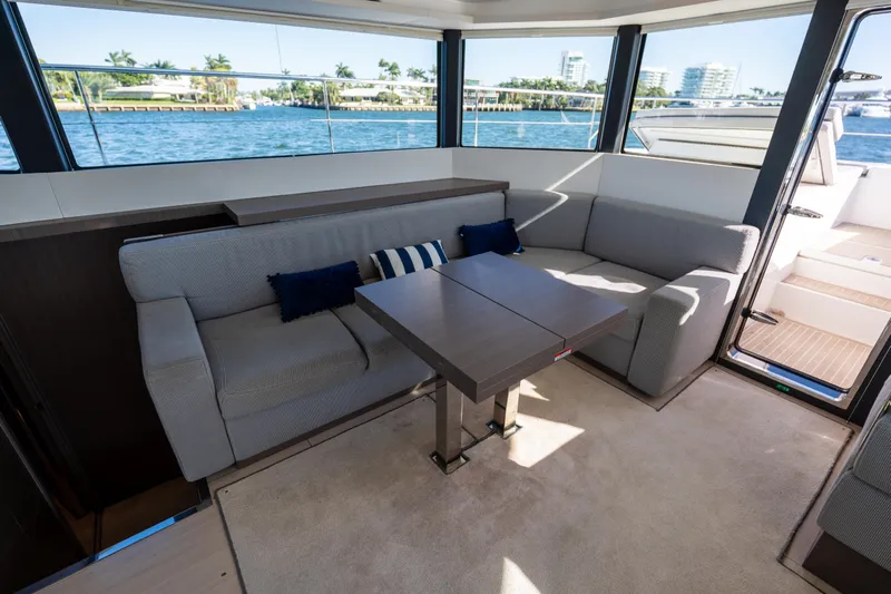 The Office Yacht Photos Pics Interior of 2021 Leopard 53 Powercat with modern seating and table, overlooking water.