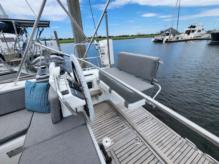 Jump Off Yacht Photos Pics Beneteau Sense 50 sailboat cockpit, 2011 model, with gray seating and wooden deck, docked at marina.