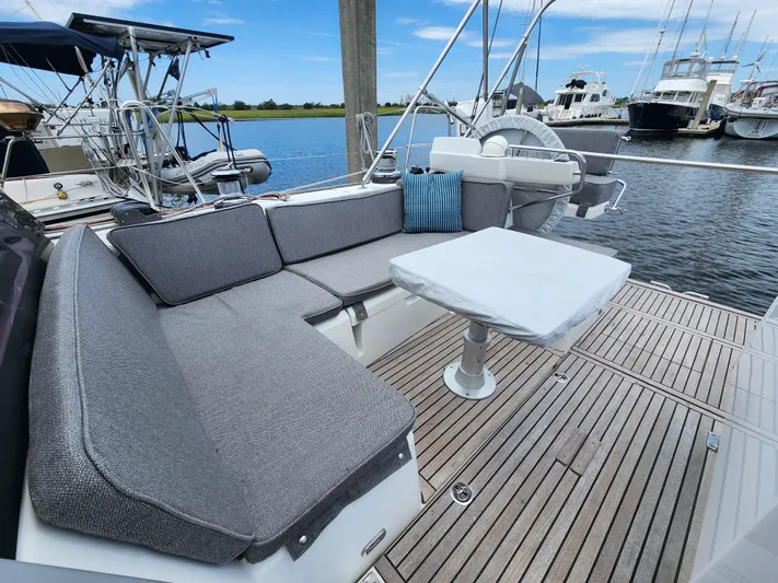 Jump Off Yacht Photos Pics Beneteau Sense 50 yacht deck with cushioned seating and table, docked at marina.