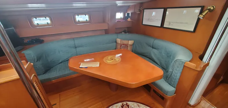 Tapestry Yacht Photos Pics Cozy interior of 1989 Tayana 55 yacht with teal seating and wooden table.