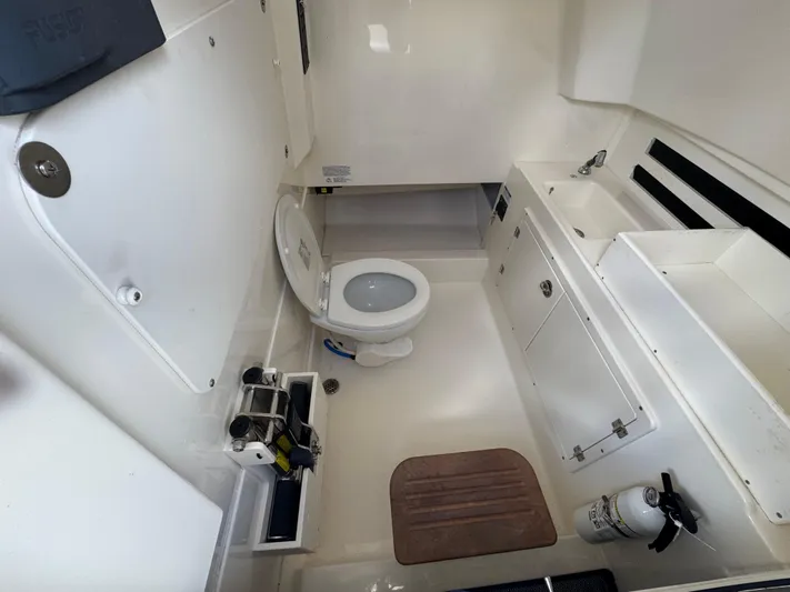  Yacht Photos Pics 2016 Boston Whaler 330 Outrage boat bathroom with toilet, sink, and storage cabinets.