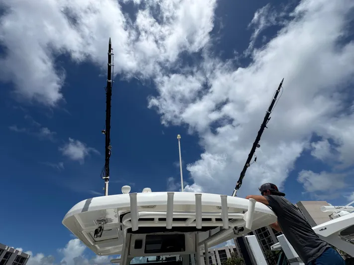  Yacht Photos Pics 2016 Boston Whaler 330 Outrage boat with fishing rods against a cloudy sky.