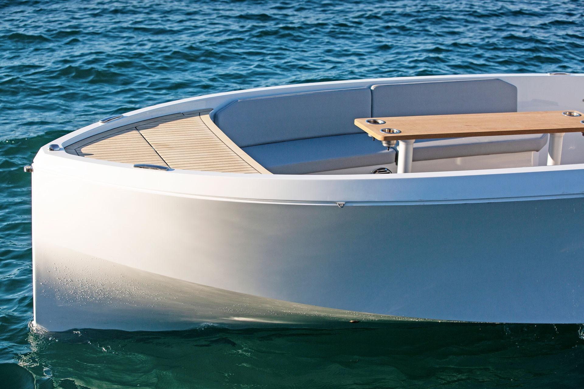 Modern Rand Mana 23 boat on calm blue water, showcasing sleek design and wooden accents.