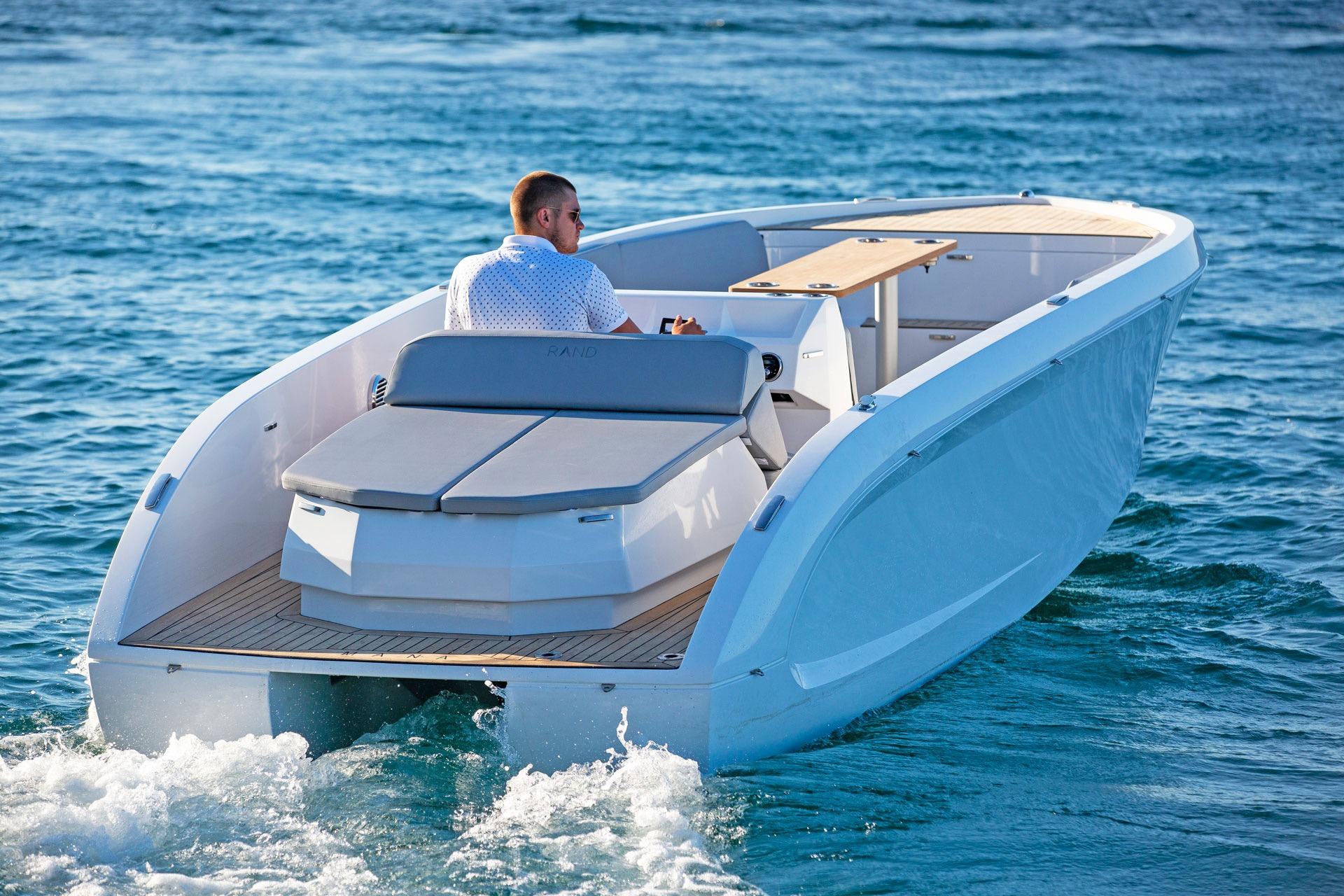 Man driving a 2021 Rand Mana 23 boat on open water.