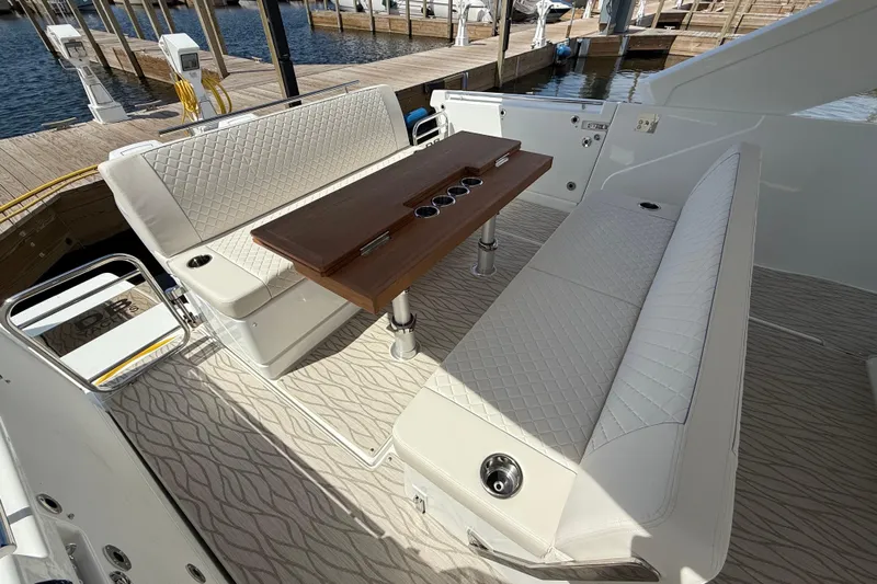  Yacht Photos Pics Luxury seating area on 2026 Jeanneau DB/37 OB yacht with elegant table and quilted upholstery.