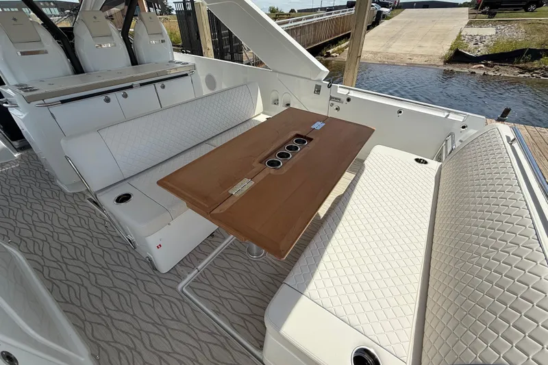  Yacht Photos Pics Luxurious seating area on 2026 Jeanneau DB/37 OB boat with elegant table and quilted upholstery.