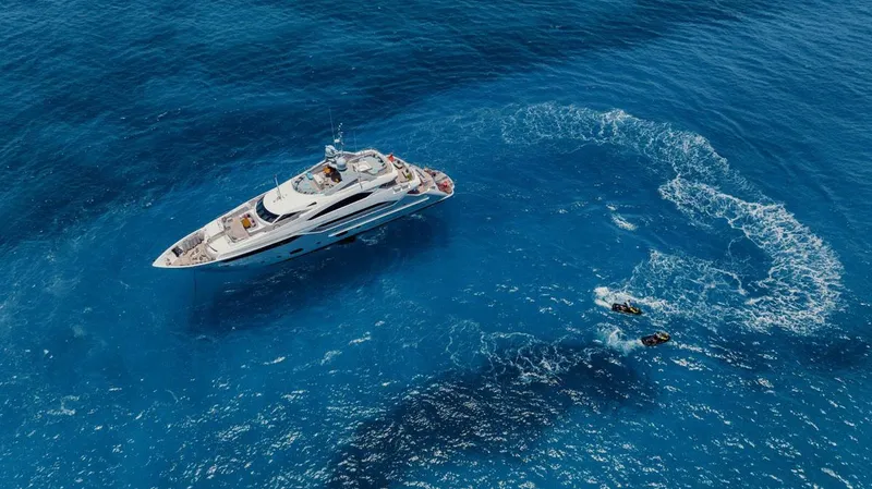 Tayrona Yacht Photos Pics Aerial view of 2012 Sunseeker 131 Yacht on vibrant blue ocean with jet skis nearby.