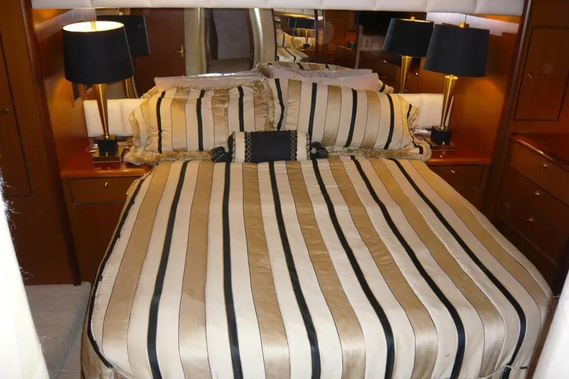 Bella Donna Yacht Photos Pics Luxurious bedroom interior of 1999 Ocean Yachts 56, featuring striped bedding and elegant lamps.
