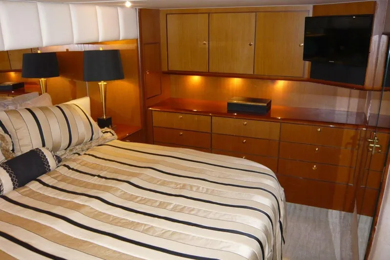 Bella Donna Yacht Photos Pics Luxurious bedroom interior of 1999 Ocean Yachts 56, featuring elegant wood cabinetry and striped bedding.