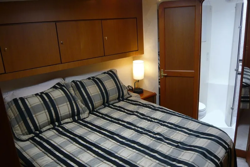 Bella Donna Yacht Photos Pics Cozy bedroom in 1999 Ocean Yachts 56, featuring striped bedding and ensuite bathroom.