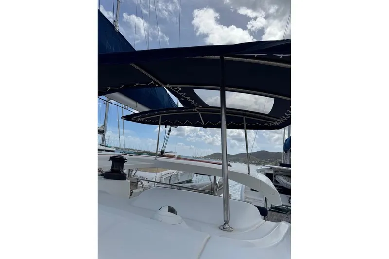  Yacht Photos Pics 2018 Lagoon 42 catamaran with sunshade, docked in a marina under a partly cloudy sky.