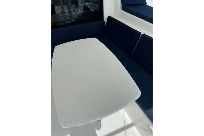  Yacht Photos Pics Interior seating area of a 2018 Lagoon 42 catamaran with a white table and blue cushions.