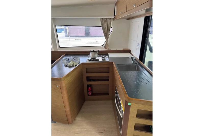  Yacht Photos Pics Interior of 2018 Lagoon 42 yacht kitchen with stove, sink, and wooden cabinetry.