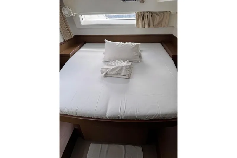  Yacht Photos Pics Interior cabin of 2018 Lagoon 42 catamaran with neatly made bed and window view.
