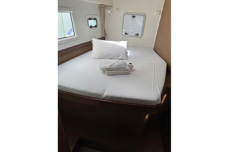  Yacht Photos Pics Cozy cabin interior of 2018 Lagoon 42 catamaran with bed and porthole windows.