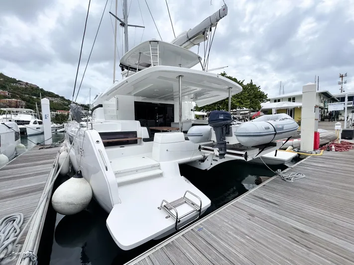 Slinky Malinki Yacht Photos Pics 2025 Lagoon 51 yacht docked, featuring spacious deck and attached dinghy.