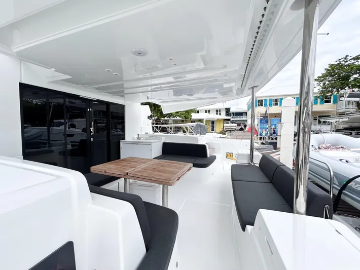Slinky Malinki Yacht Photos Pics Spacious deck of 2025 Lagoon 51 yacht with modern seating and wooden table.