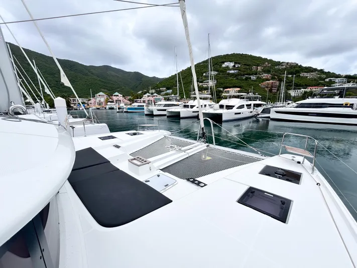 Slinky Malinki Yacht Photos Pics 2025 Lagoon 51 catamaran docked in a scenic marina with lush hills in the background.