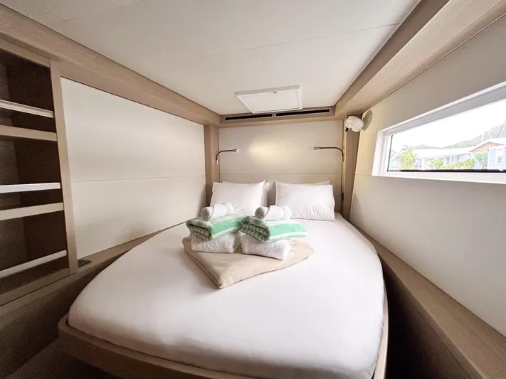 Slinky Malinki Yacht Photos Pics Luxurious cabin interior of 2025 Lagoon 51 yacht with cozy bed and window view.