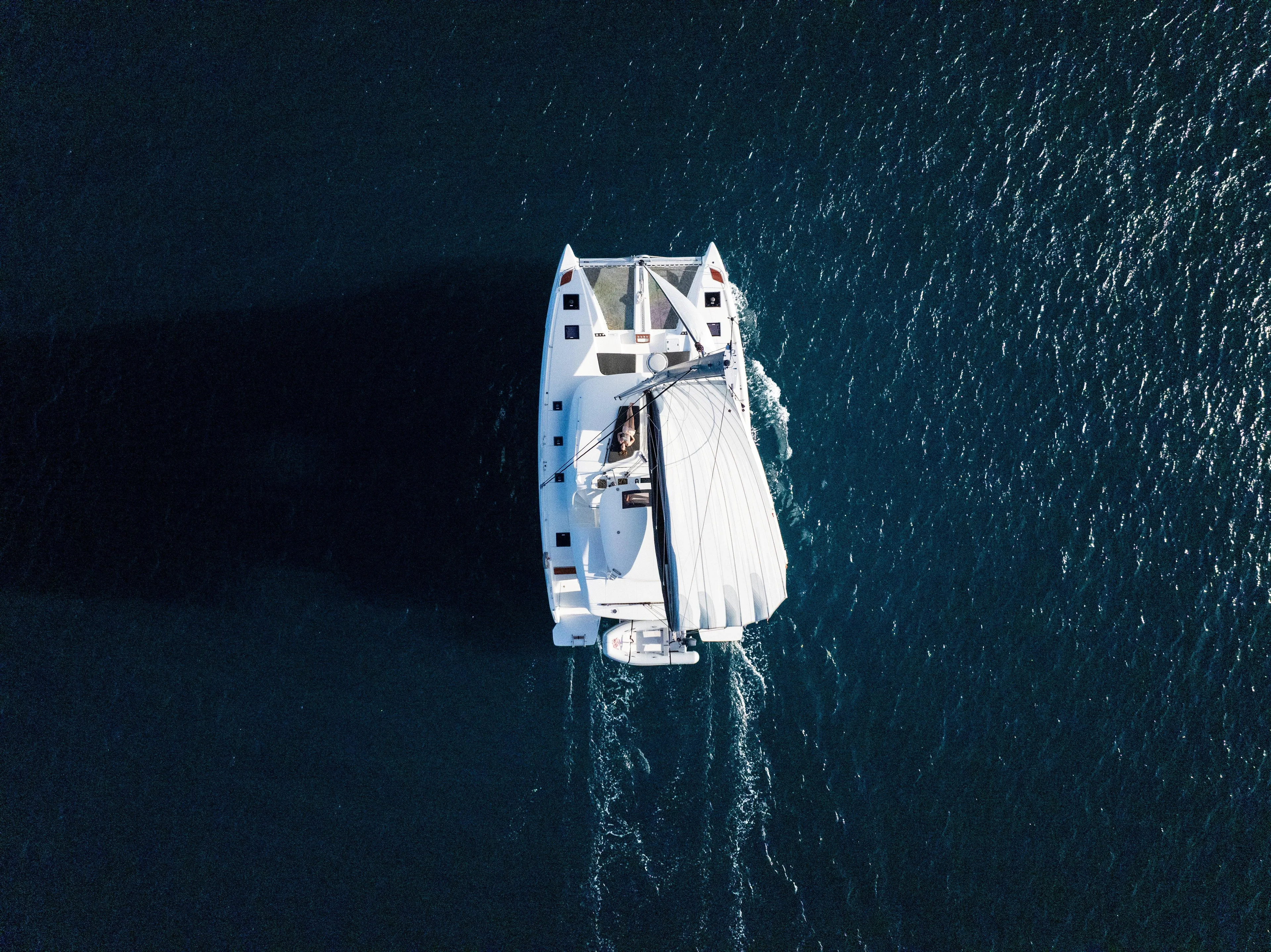 Slinky Malinki Yacht Photos Pics Aerial view of 2025 Lagoon 51 catamaran sailing on open water.