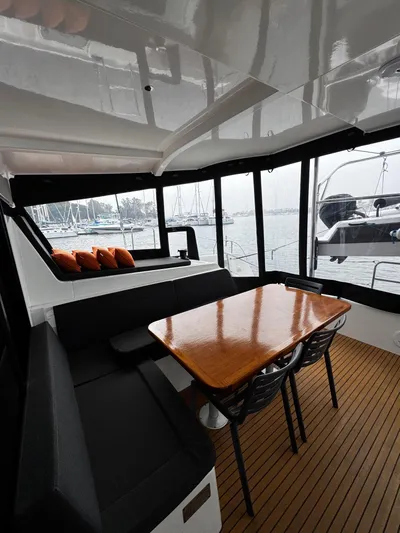 Nellie Yacht Photos Pics Interior of 2020 Lagoon 42 catamaran with wooden table and marina view.