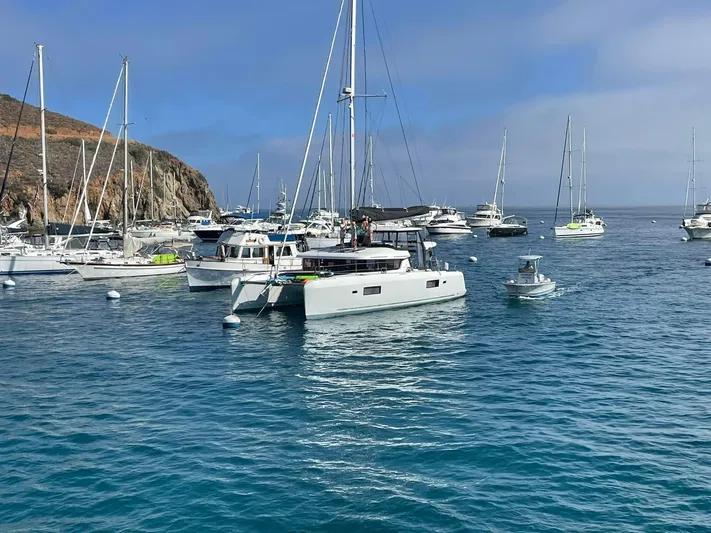 Nellie Yacht Photos Pics A 2020 Lagoon 42 catamaran anchored among various boats in a scenic harbor.