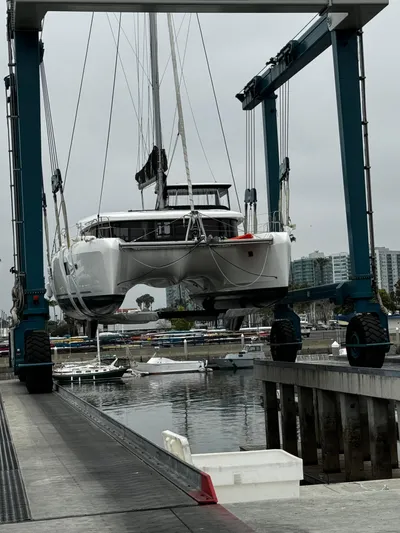 Nellie Yacht Photos Pics 2020 Lagoon 42 catamaran being lifted at a marina with overcast skies.