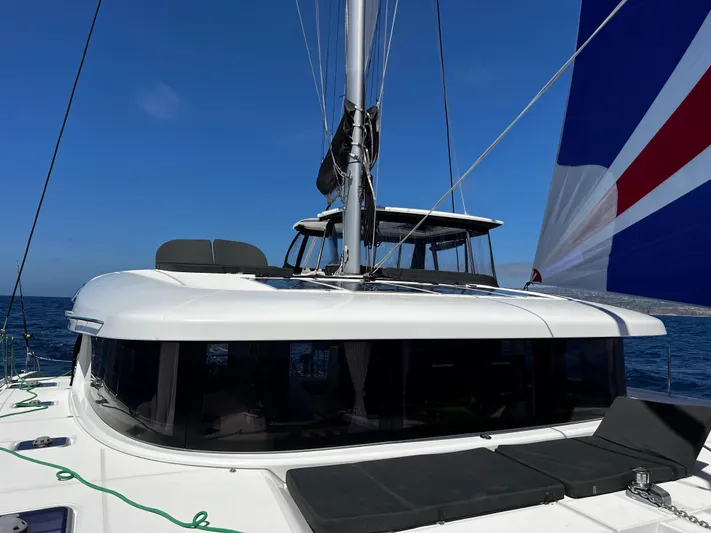 Nellie Yacht Photos Pics 2020 Lagoon 42 catamaran sailing on open sea with blue sky background.