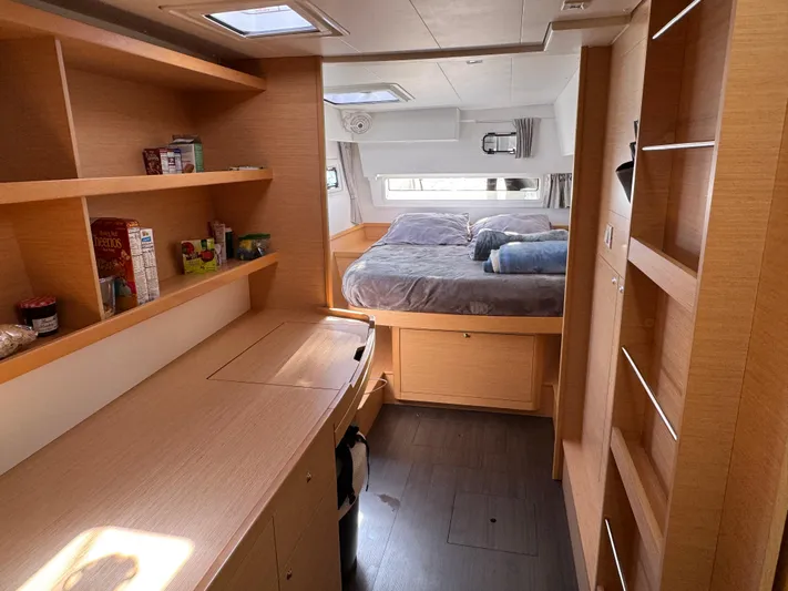 Nellie Yacht Photos Pics Luxurious interior of 2020 Lagoon 42 catamaran with cozy bedroom and wooden cabinetry.