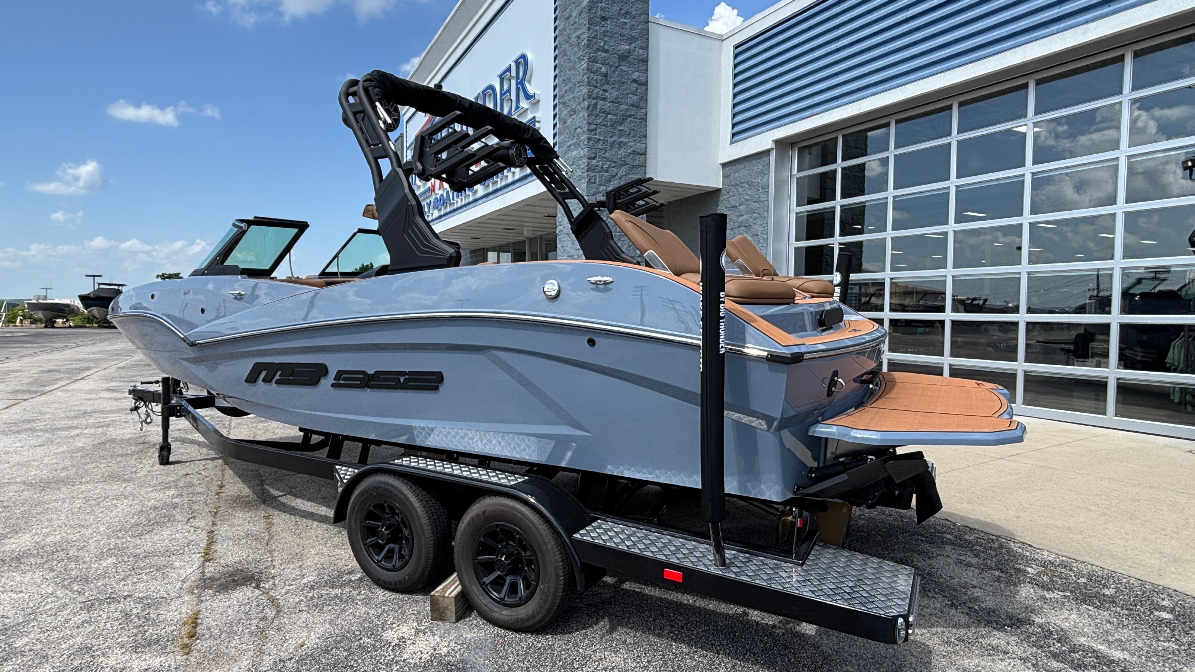 2025 MB B52 23 Alpha boat on trailer, parked outside dealership.