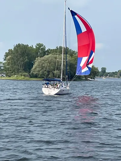 Amadeus Yacht Photos Pics Sailboat Catalina 355 (2014) with colorful spinnaker on a lake, surrounded by trees.