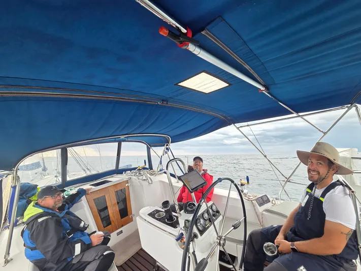 Amadeus Yacht Photos Pics Three people sailing on a 2014 Catalina 355 yacht under a blue canopy.