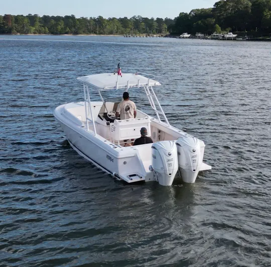  Yacht Photos Pics 2002 Intrepid 323 Cuddy boat cruising on a calm lake with two passengers.