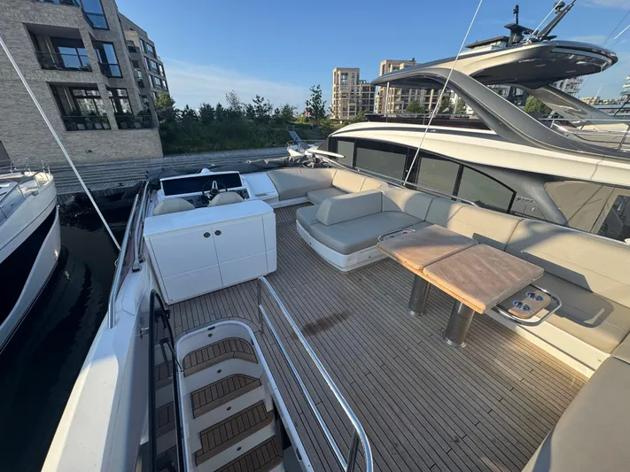  Yacht Photos Pics Luxurious 2020 Princess F55 yacht deck with seating and tables, docked near modern buildings.