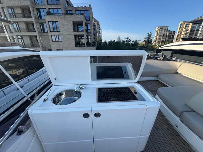  Yacht Photos Pics Outdoor kitchen on a 2020 Princess F55 yacht with grill and sink, docked near modern buildings.