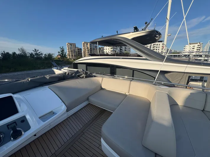  Yacht Photos Pics Luxurious 2020 Princess F55 yacht with spacious deck and modern seating, docked near waterfront buildings.