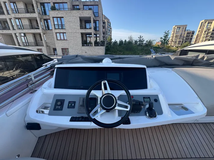  Yacht Photos Pics Helm of 2020 Princess F55 yacht with modern controls, docked near urban buildings.