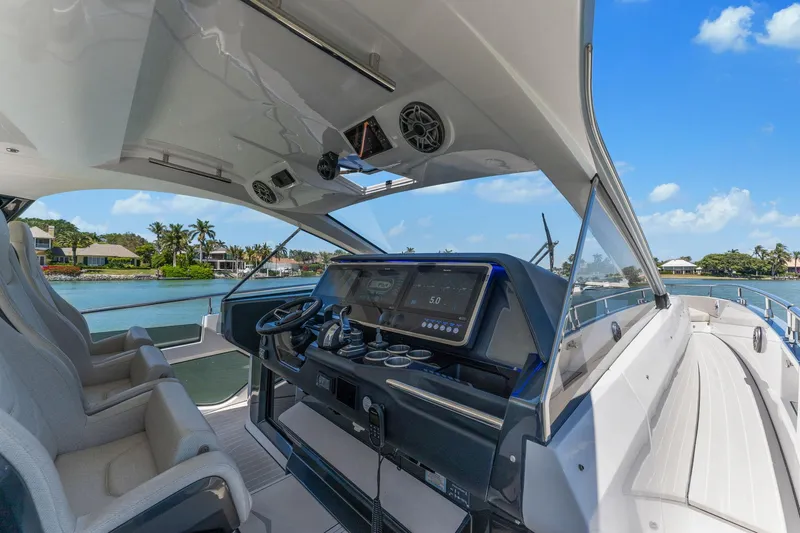 Why Knot Yacht Photos Pics 2022 Azimut 47 VERVE yacht cockpit with modern controls, overlooking serene waterfront.