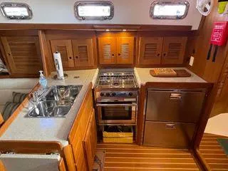 Top O Nok Yacht Photos Pics Modern galley kitchen in 2020 Tartan 395 yacht with wood cabinetry and stainless steel appliances.